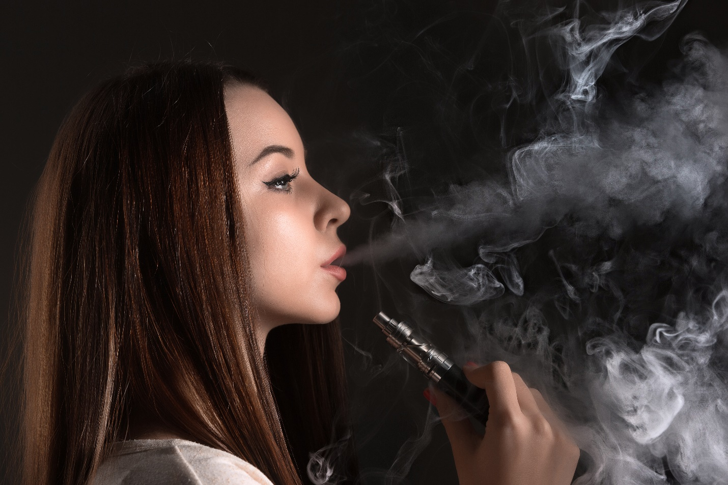 A woman smoking her vape in front a black background