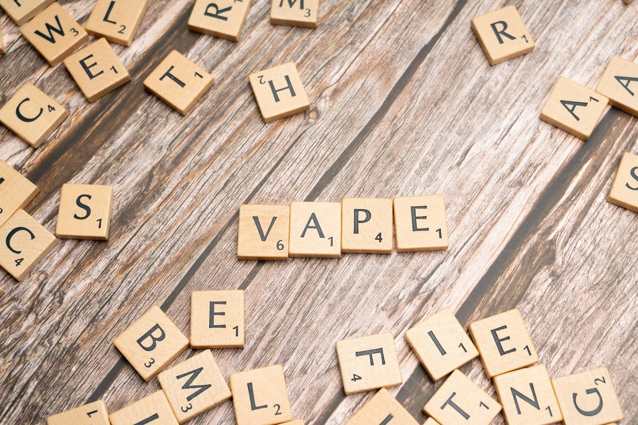 Scrabble pieces spelling “Vape” on a wooden table